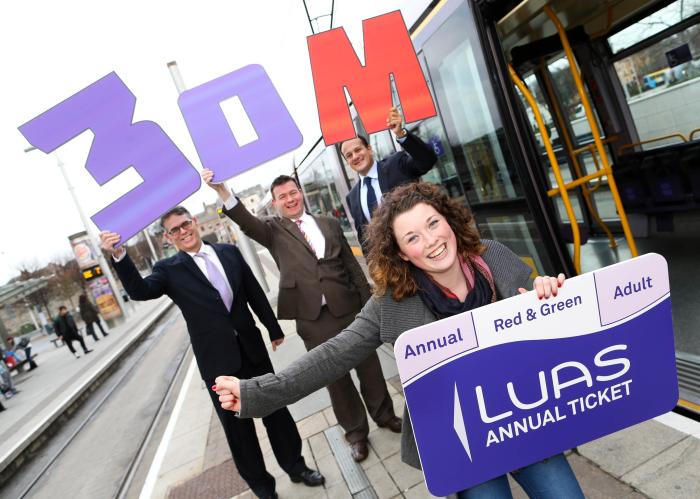 Image of four people, including Leo Varadkar and Alan Kelly, beside the luas holding a 30 million banner and a large luas ticket. 